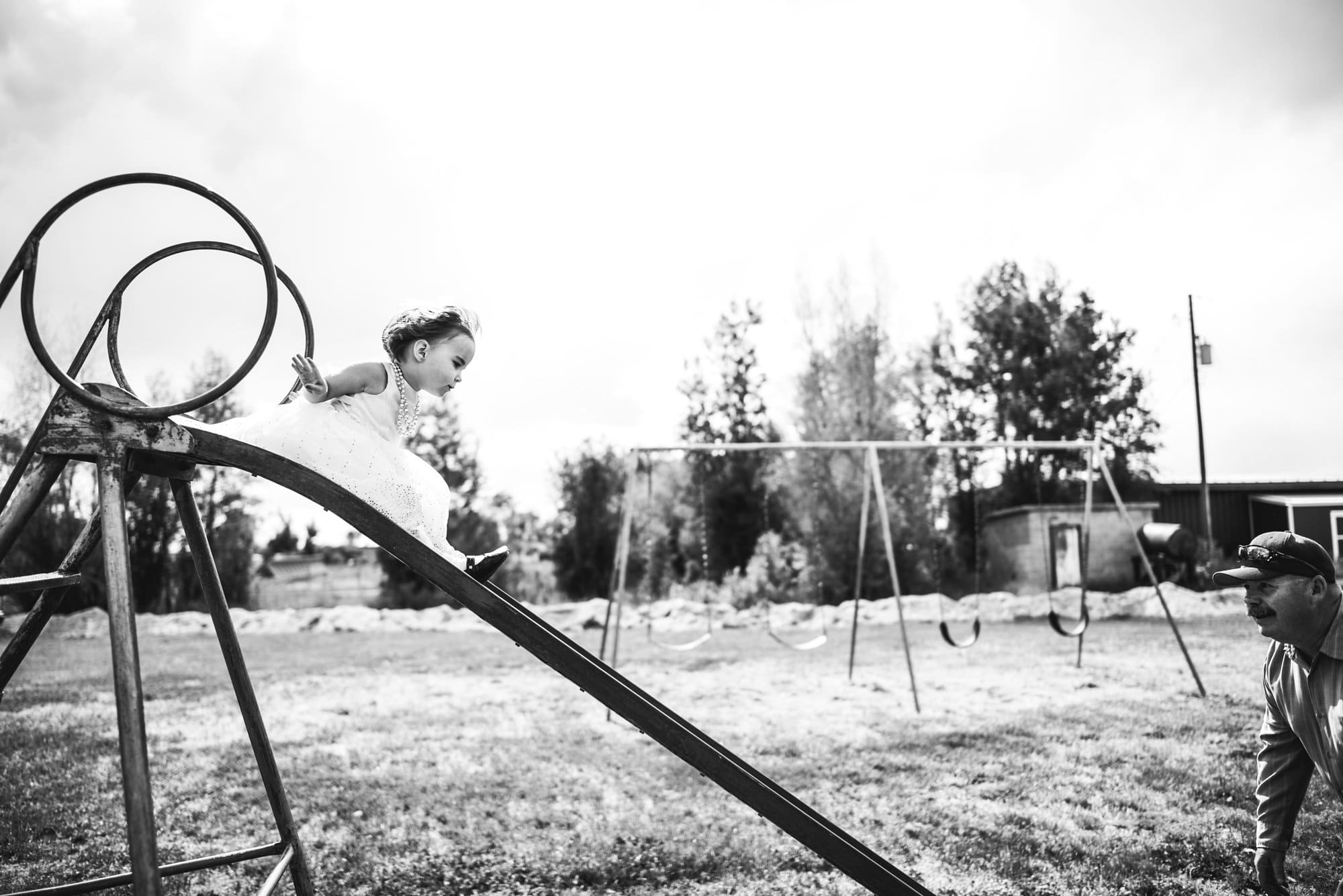 girl sliding down slide in dress