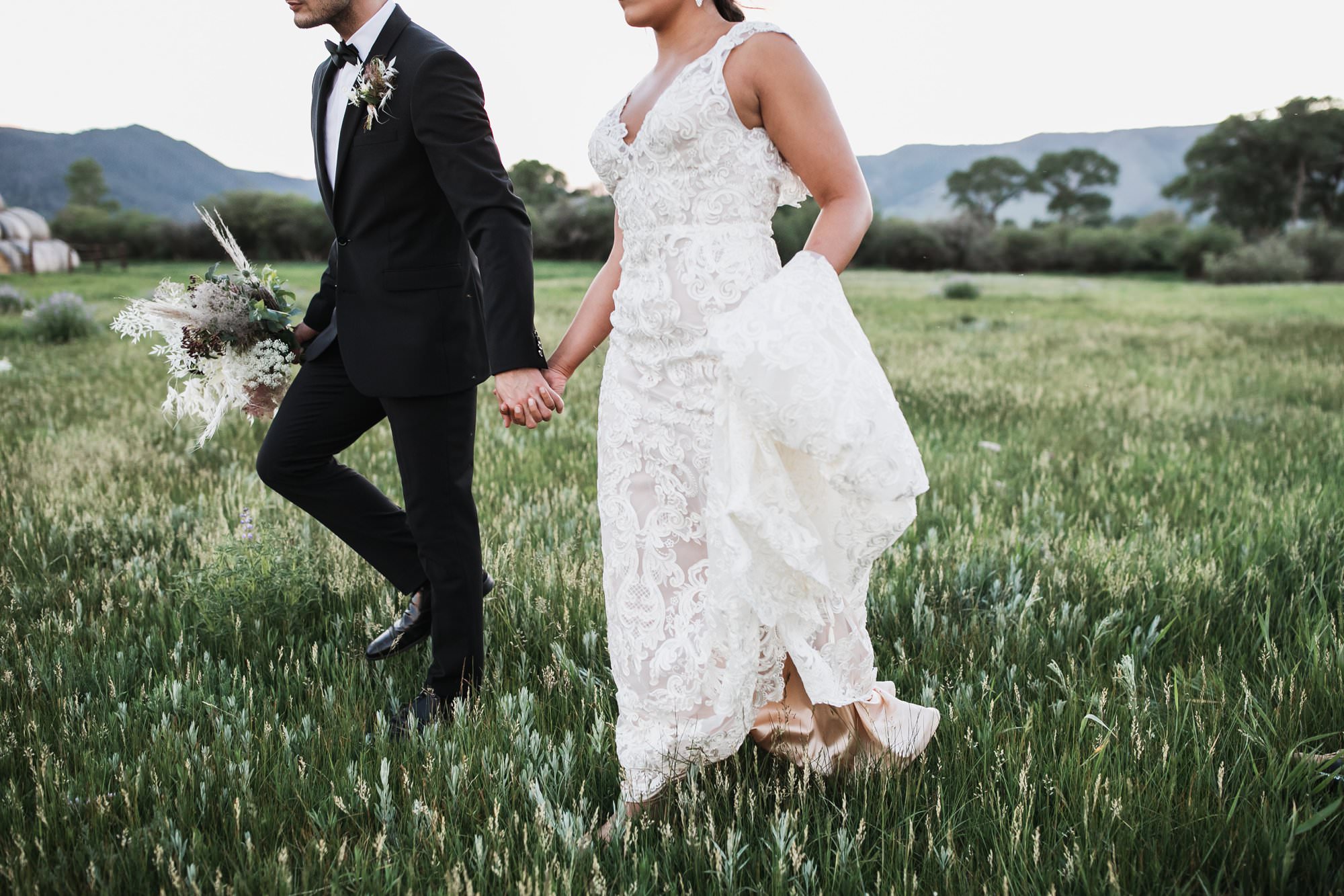 bride and groom walking through field