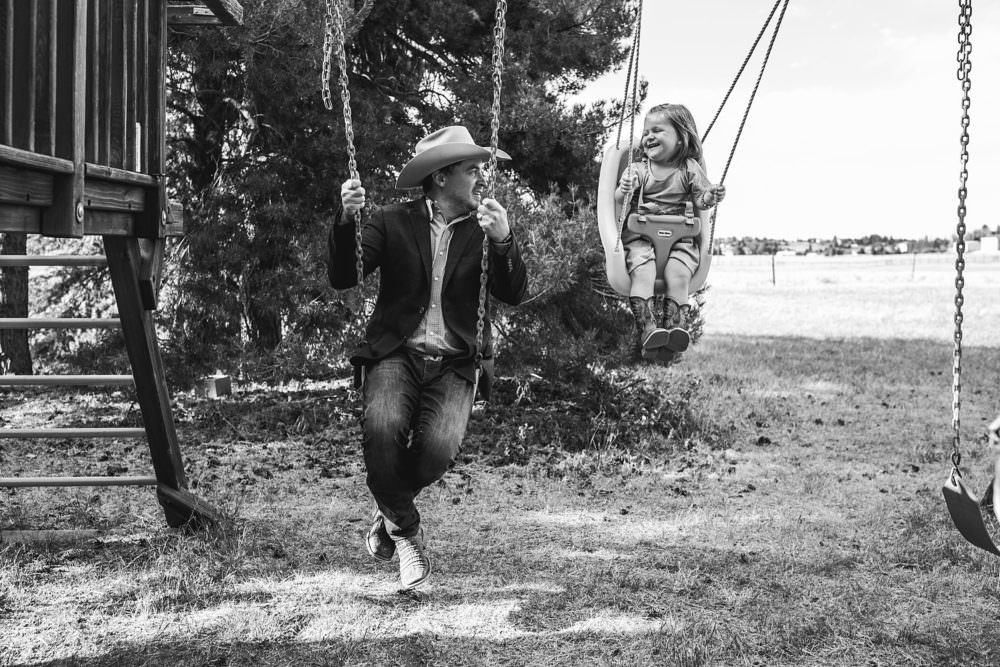 cowboy swinging with little girl at wedding in wyoming