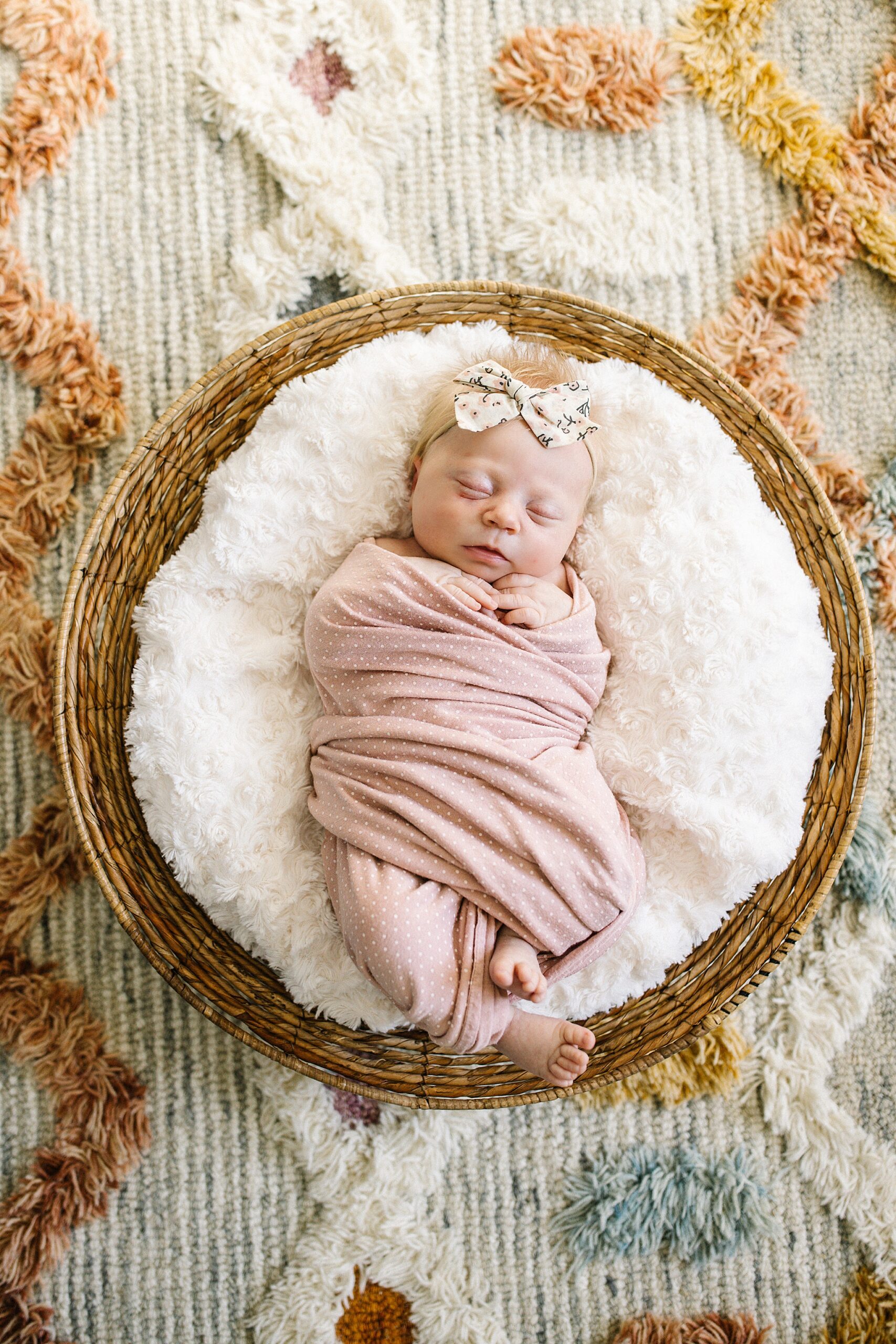 newborn baby in basket with tasteful bow in hair